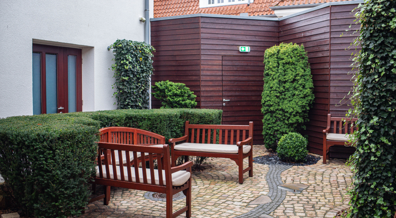 Begrünte Sitzecke im Innenhof mit Bänken und Auflagen