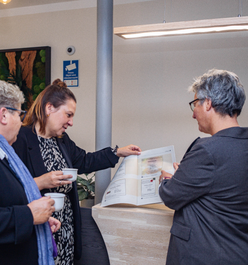 Drei Frauen schauen eine Broschüre mit Anzeigen an.